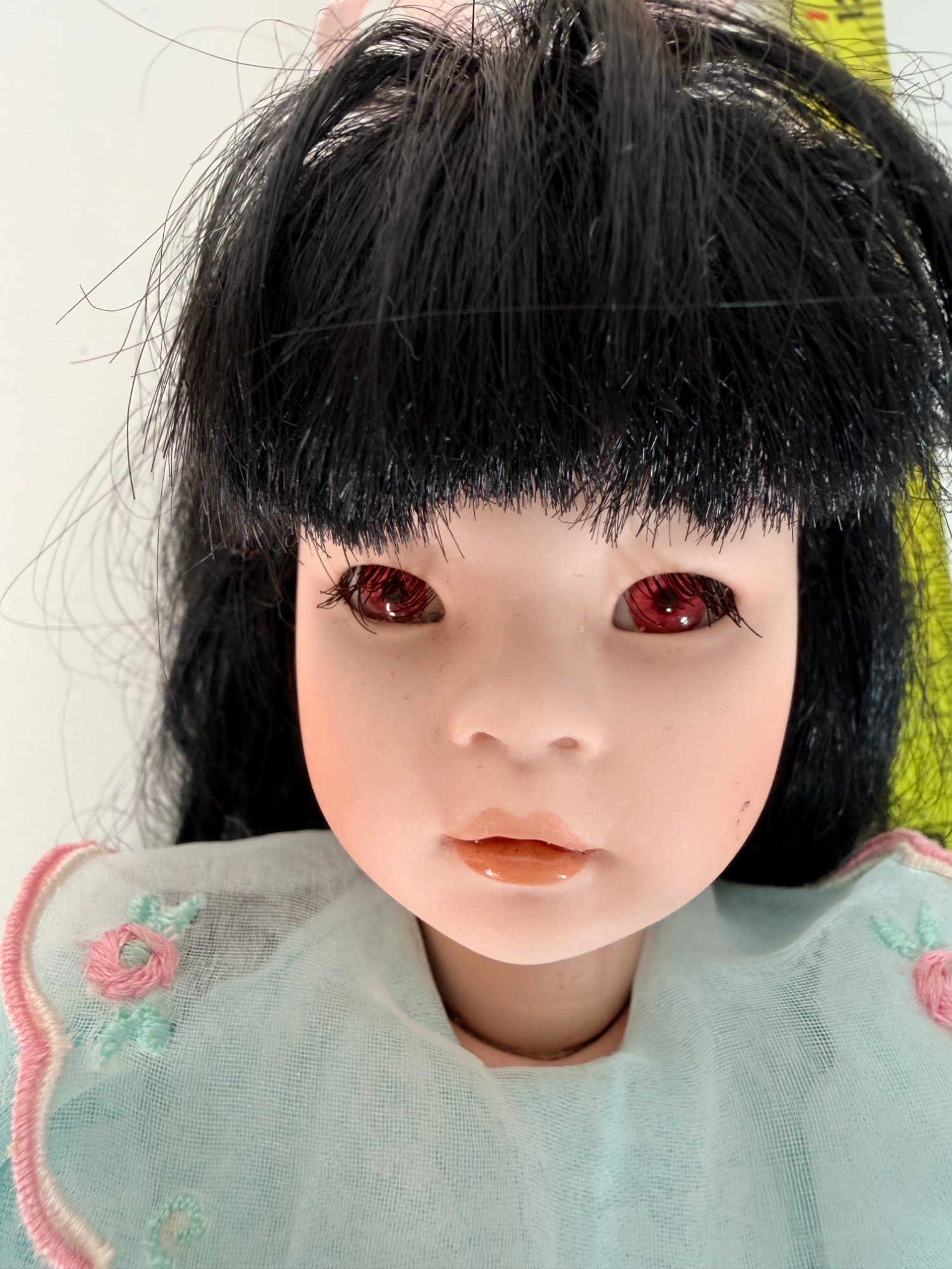 Porcelain collectible doll with black hair and mint floral dress
